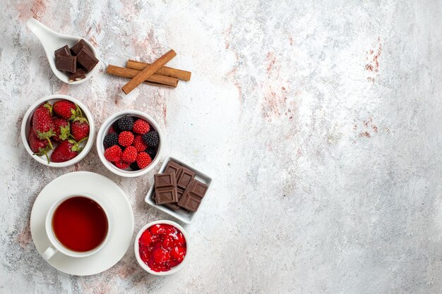 Vue de dessus de la tasse de thé avec de la confiture de fraises et des confitures sur une surface blanche