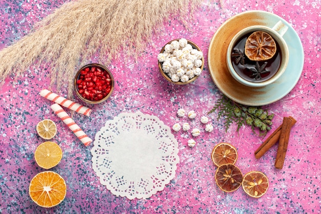 Vue de dessus tasse de thé avec des confitures sucrées blanches et de la cannelle sur un bureau rose