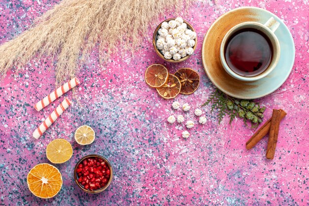 Vue de dessus tasse de thé avec confitures sucrées blanches et cannelle sur surface rose