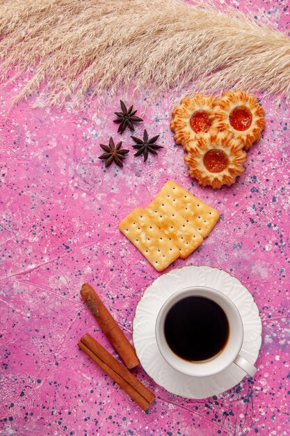 Vue de dessus tasse de thé avec des craquelins et des biscuits sur le bureau rose biscuit cookei croustillant sucre sucré