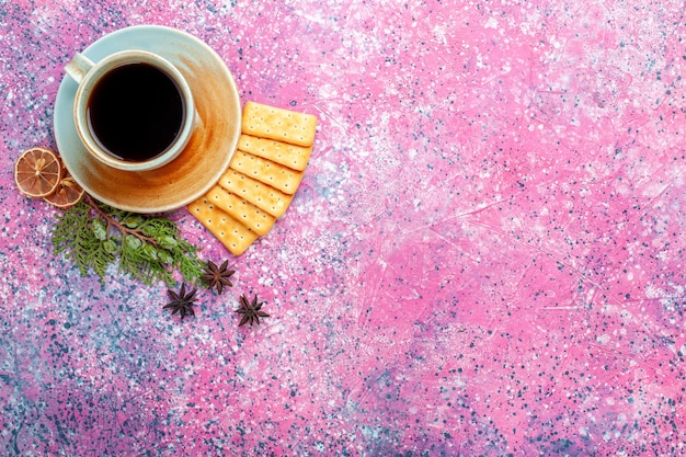 Vue de dessus tasse de thé avec des craquelins sur le bureau rose