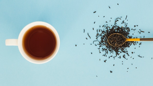 Vue de dessus tasse de thé avec une cuillère pleine de feuilles sèches