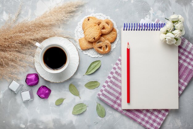 Vue de dessus de la tasse de thé avec de délicieux petits biscuits bonbons au chocolat sur gris clair, biscuit biscuit sucre thé sucré