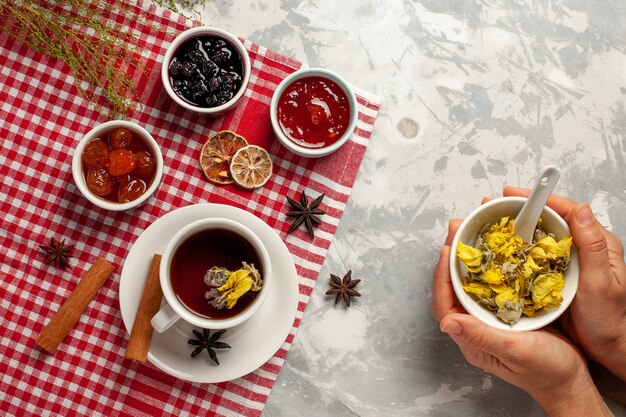 Vue de dessus tasse de thé avec dessert et différentes confitures sur fond blanc léger thé de confiture de fruits sucre sucré