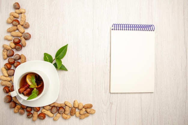 Vue de dessus tasse de thé avec différentes noix sur un bureau blanc couleur thé fruits cérémonie noix