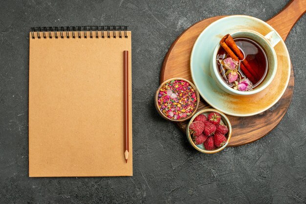 Vue de dessus tasse de thé avec des fleurs et bloc-notes sur fond gris thé boisson couleur cérémonie fleur