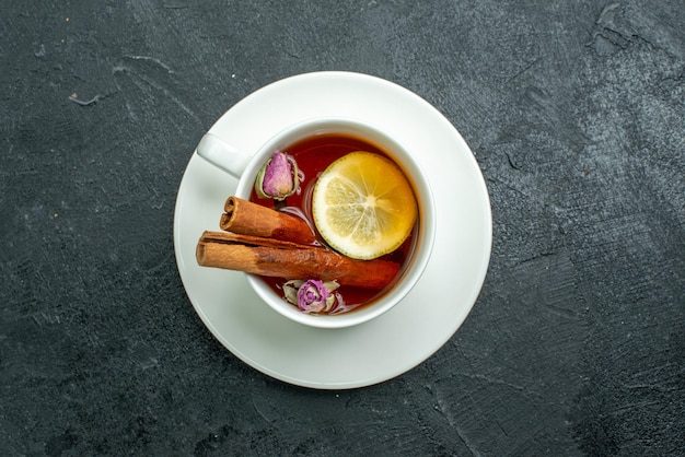 Vue de dessus tasse de thé avec des fleurs et du thé sur une surface sombre cérémonie des agrumes aux fruits du thé