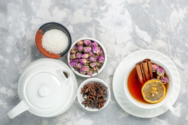 Vue de dessus tasse de thé avec des fleurs séchées et une bouilloire sur une surface blanche