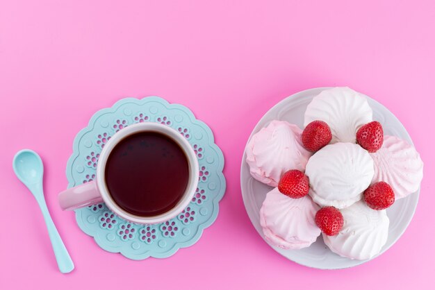Une vue de dessus tasse de thé avec des fraises rouges et des meringues sur rose, confiserie de biscuits à l'heure du thé