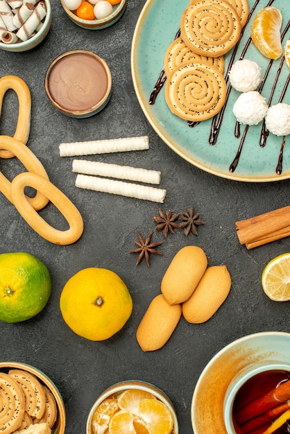 Vue de dessus tasse de thé avec des fruits et des biscuits sur le fond sombre