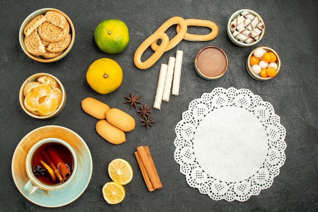 Vue de dessus tasse de thé avec des fruits et des biscuits sur le fond sombre