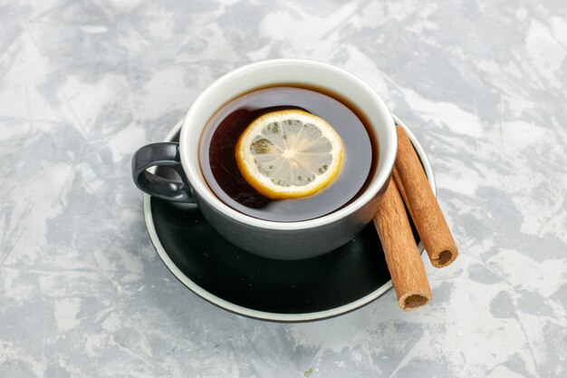 Vue de dessus tasse de thé à l'intérieur de la tasse et de l'assiette à la cannelle sur une surface blanche