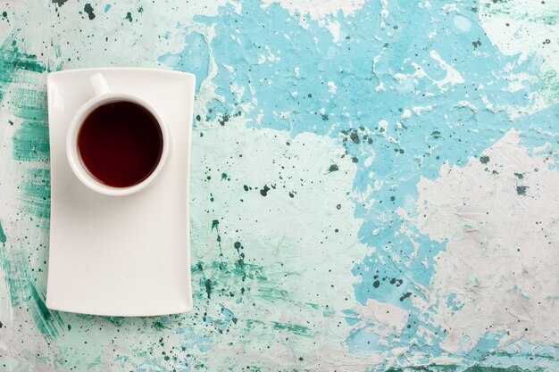 Vue de dessus tasse de thé à l'intérieur de la tasse et de l'assiette sur une surface bleu clair