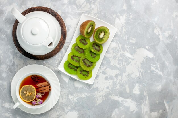 Vue de dessus tasse de thé avec des kiwis frais sur la surface blanche