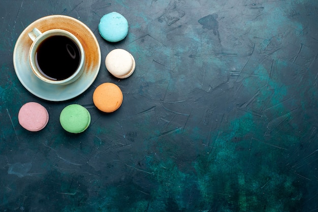 Vue de dessus tasse de thé avec des macarons français sur backgruond bleu foncé cuire gâteau tarte sucre thé sucré