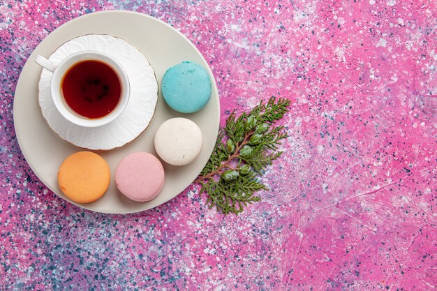 Vue de dessus tasse de thé avec des macarons français colorés sur la surface rose