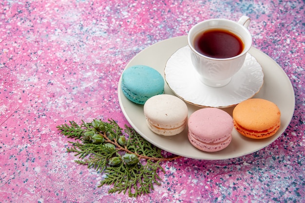 Vue de dessus tasse de thé avec des macarons français colorés sur la surface rose