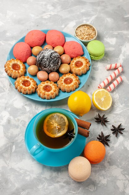 Vue de dessus tasse de thé avec macarons français petits biscuits et gâteaux sur surface blanche