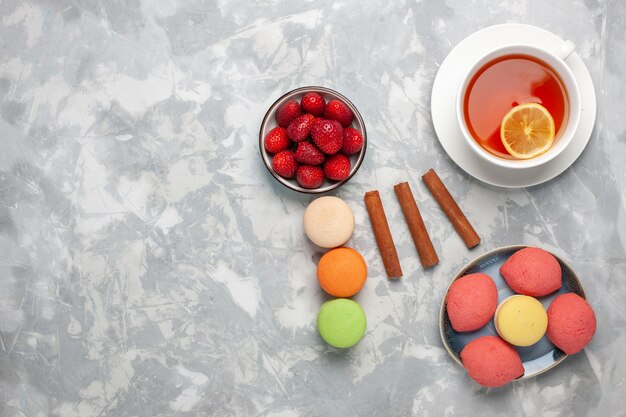 Vue de dessus tasse de thé avec des macarons et des gâteaux sur une surface blanc clair