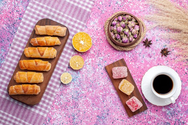 Vue de dessus tasse de thé avec des morceaux de marmelade et des bagels sur le bureau rose.