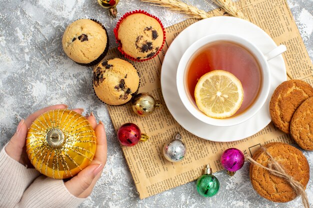 Vue De Dessus D'une Tasse De Thé Noir Et D'accessoires De Décoration Sur Un Vieux Biscuits En Papier Et De Petits Cupcakes Sur La Surface De La Glace