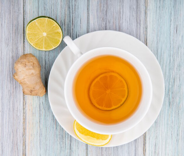 Vue de dessus d'une tasse de thé noir avec des tranches de citron avec du gingembre sur bois gris