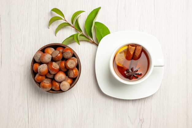 Vue de dessus tasse de thé avec des noisettes fraîches sur une cérémonie de collation de noix de thé de bureau blanc