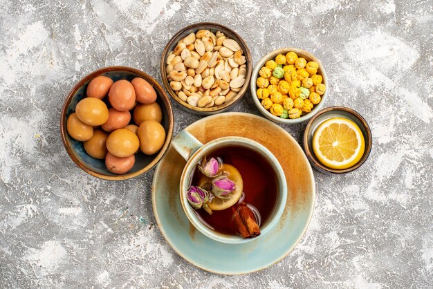 Vue de dessus de la tasse de thé avec des noix et des bonbons sur une surface blanche claire