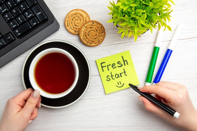 Vue de dessus tasse de thé avec des notes de motivation écrites sur fond blanc sweet business clavier pause job travailleur bureau