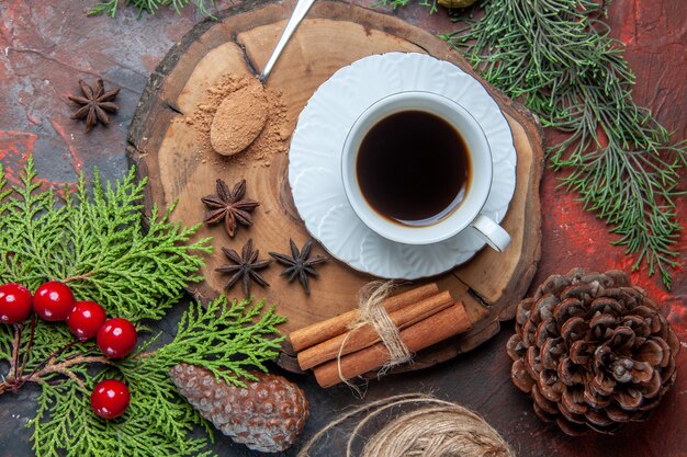 Vue de dessus une tasse de thé sur planche de bois bâtons de cannelle pomme de pin anis sur fond sombre