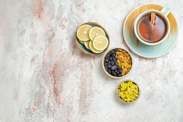 Vue de dessus tasse de thé avec raisins secs et tranches de citron sur une surface blanche thé aux fruits boisson aux agrumes