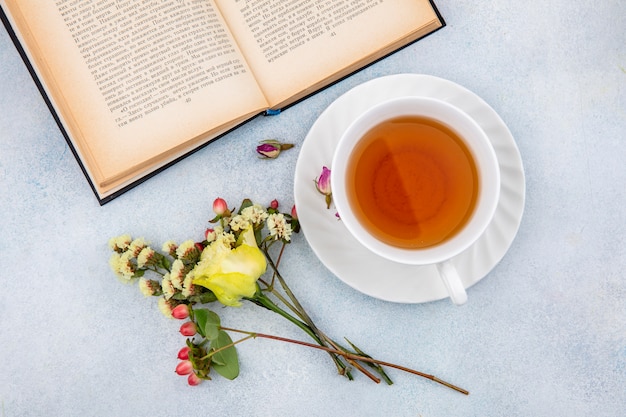 Photo gratuite vue de dessus d'une tasse de thé avec rose jaune avec des baies d'hypericum sur blanc