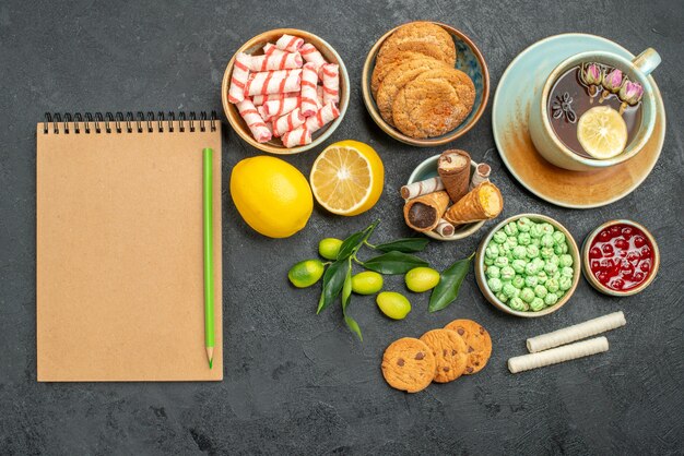 Vue de dessus une tasse de thé une tasse de tisane agrumes bonbons biscuits confiture cahier crayon