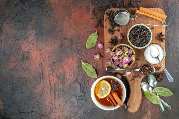 Vue de dessus tasse de thé avec thé noir et fleurs séchées sur fond marron foncé couleur de l'eau de thé petit déjeuner biscuit photo boisson cérémonie