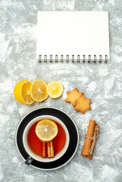 Vue de dessus une tasse de thé tranches de citron cannelle cahier sur surface grise