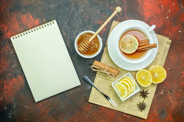 Photo gratuite vue de dessus tasse de thé avec des tranches de citron dans un petit bol sur une table rouge foncé