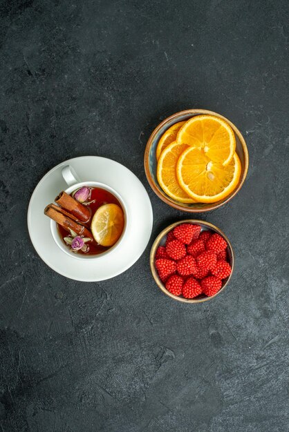 Vue de dessus tasse de thé avec tranches d'orange et confitures sur la surface sombre thé aux agrumes aux fruits