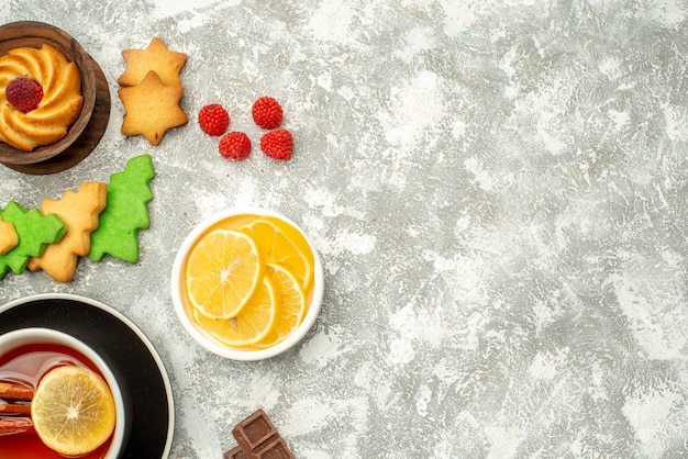 Vue de dessus tasse de tranches de citron biscuit thé dans des bols sur l'espace libre de surface grise