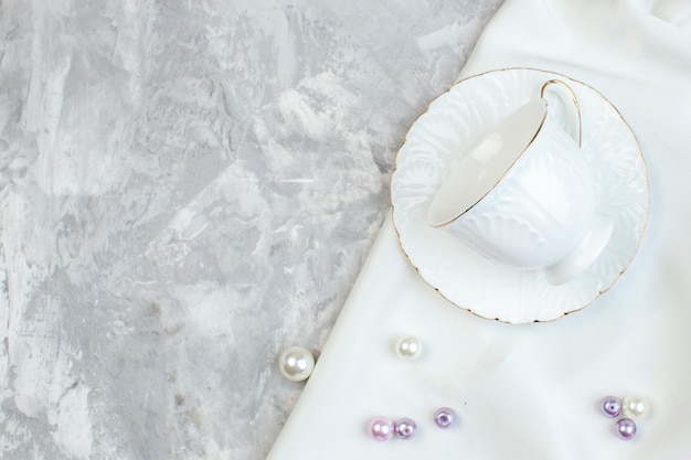 Vue de dessus des tasses élégantes avec de belles perles sur une surface blanche photo horizontale couleur de verre photo féminin