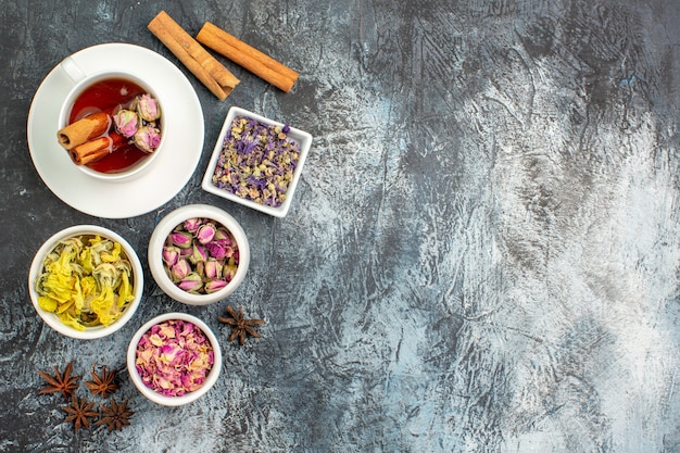 Vue de dessus de la tisane avec des bâtons de cannelle et des fleurs sèches sur fond gris