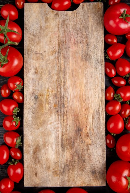 Vue de dessus des tomates autour d'une planche à découper sur bois