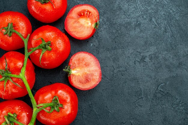 Vue de dessus des tomates de branche de tomate rouge coupées en deux sur une table noire avec un espace libre