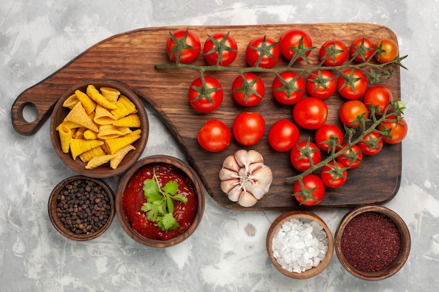 Photo gratuite vue de dessus tomates cerises fraîches avec différents assaisonnements sur une surface blanche