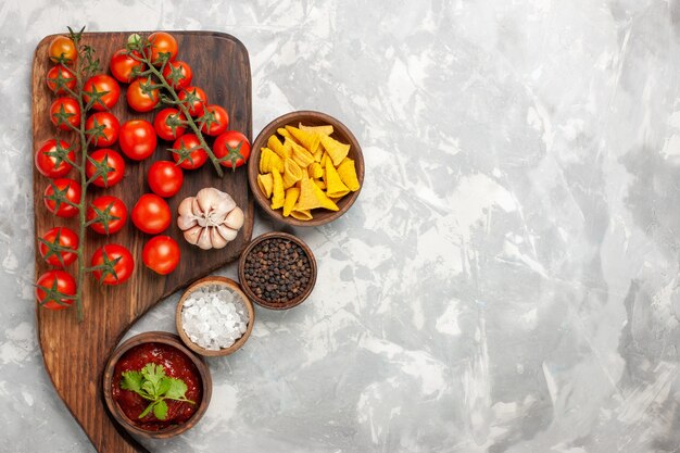 Vue de dessus tomates cerises fraîches avec différents assaisonnements sur une surface blanche