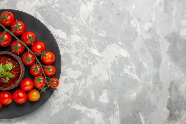 Vue de dessus tomates cerises fraîches à l'intérieur de la plaque sur le bureau blanc