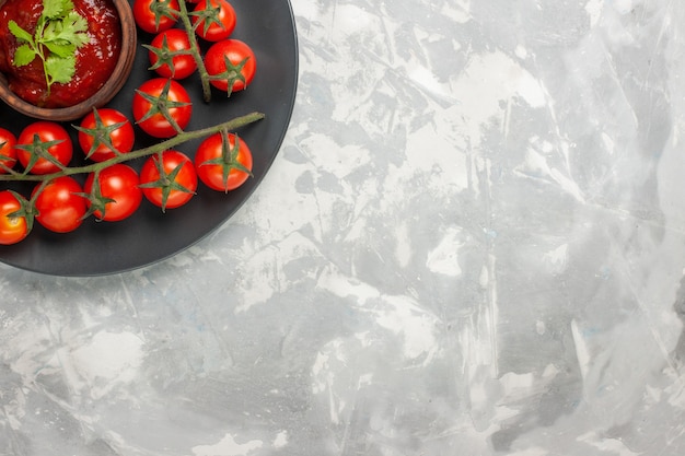 Vue de dessus tomates cerises fraîches à l'intérieur de la plaque sur la surface blanche