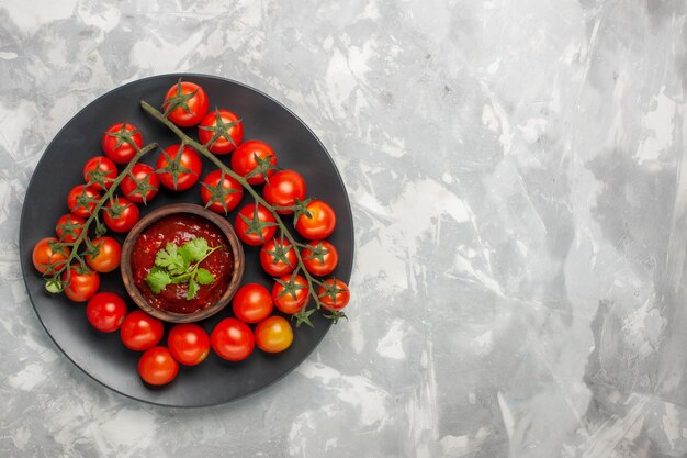 Photo gratuite vue de dessus tomates cerises fraîches à l'intérieur de la plaque sur la surface blanche