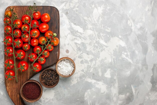 Vue de dessus tomates cerises fraîches légumes entiers mûrs avec assaisonnements sur surface blanche