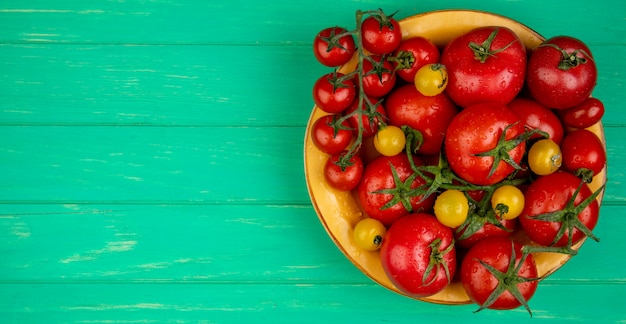 Vue de dessus des tomates dans un bol sur le côté droit et vert avec copie espace