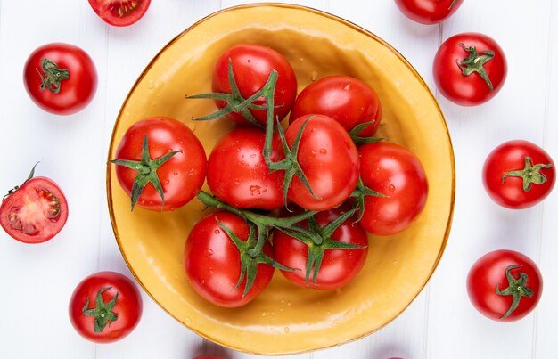 Vue de dessus des tomates dans un bol avec des morceaux entiers et sur une surface en bois